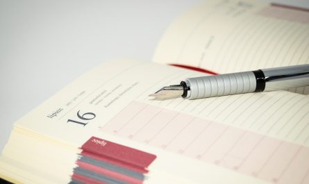 Photo of an opened schedule planner with a fountain pen laying across it